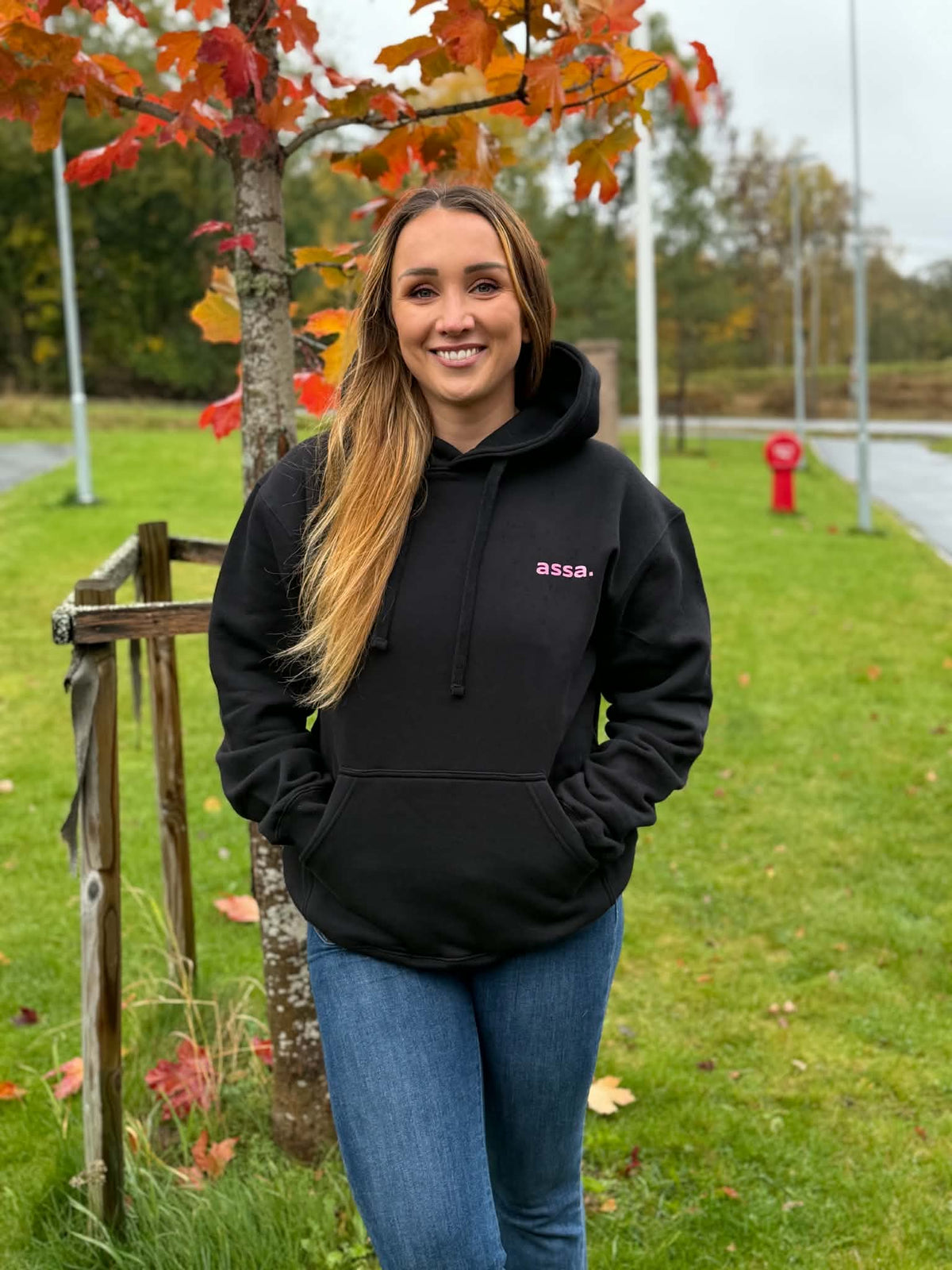 Svart assa.-hoody med rosa glittertrykk, vist på modell